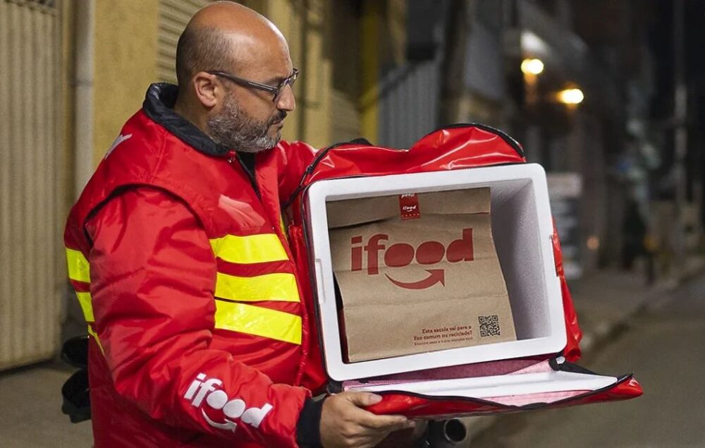 Entregador do iFood abrindo a mochila para retirar a refeição e concluir a entrega.