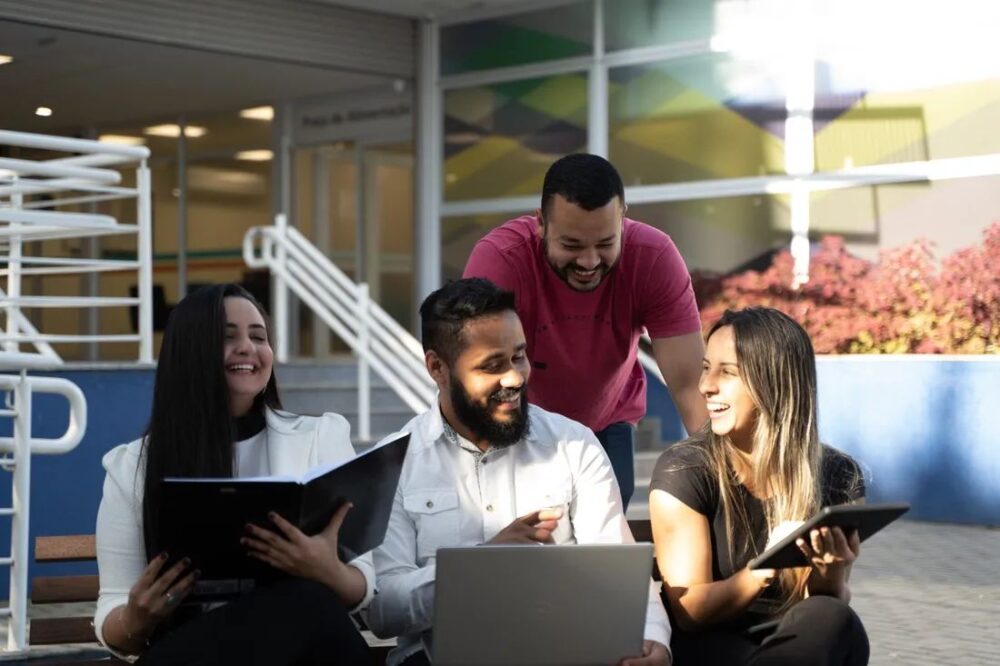 Grupo de estudantes sorridentes reunidos no pátio de uma instituição de ensino da Yduqs.