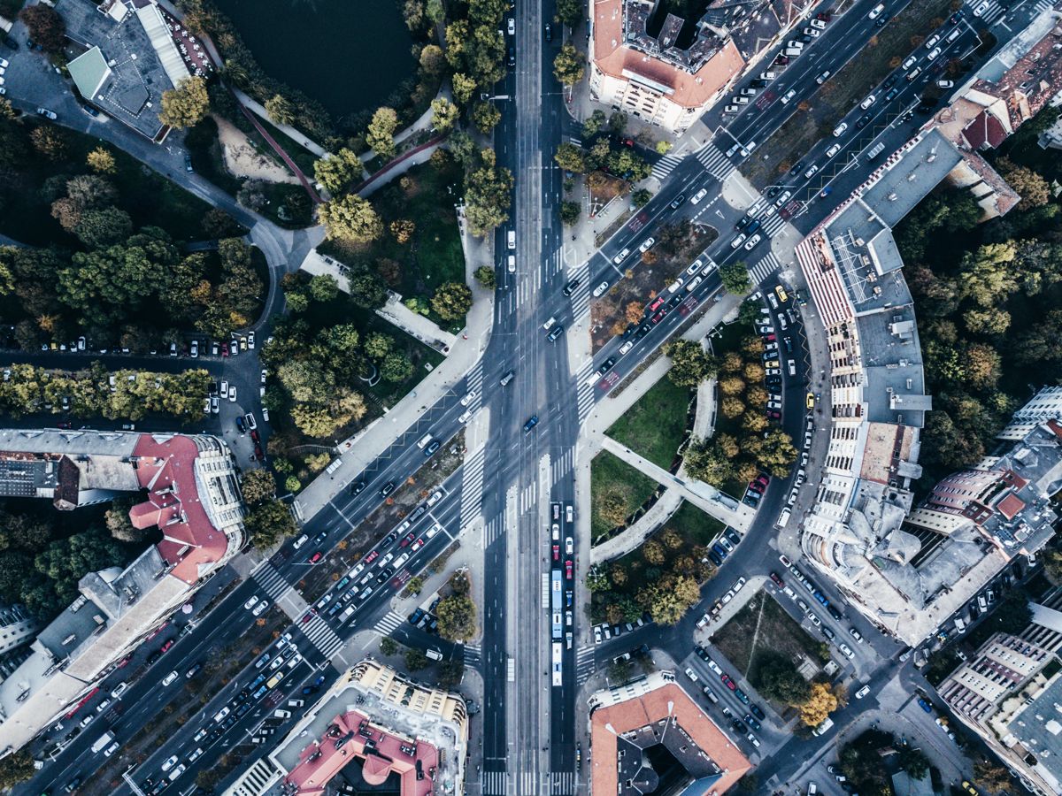 Vista aérea de um movimentado cruzamento de avenidas em um centro urbano, com intenso fluxo de veículos.