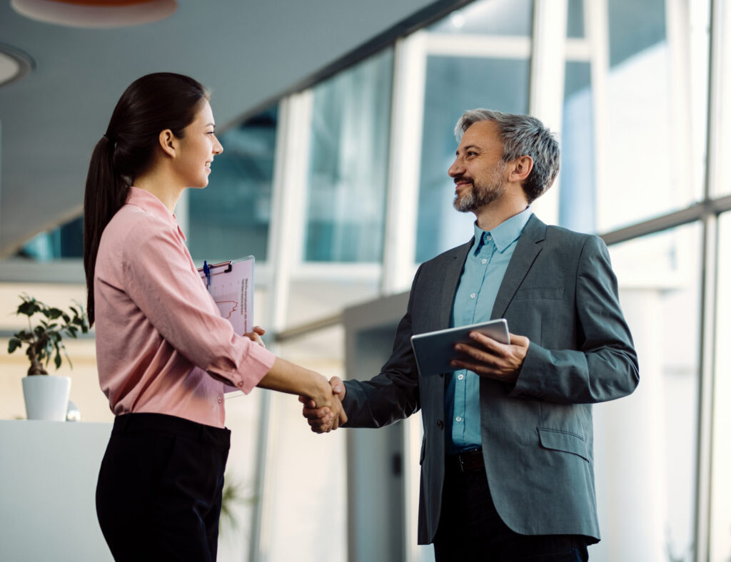 Um homem e uma mulher apertando as mãos após fecharem um novo negócio.